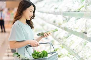 het jonge meisje kiest ervoor om groenten te kopen in de supermarkt