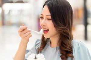 jong meisje zit alleen slagroomtaart te eten in het winkelcentrum foto