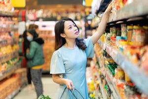 jong meisje kiest ervoor om levensmiddelen te kopen in de supermarkt foto