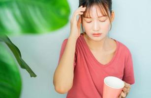 jonge aziatische vrouw drinkt koffie en voelt zich verdrietig