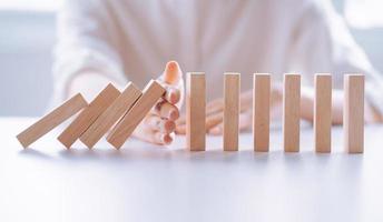 vrouwenhand stop houten domino bedrijfscrisiseffect, risicobeschermingsconcept