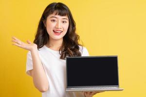 jonge Aziatische vrouw met laptop op gele achtergrond yellow foto