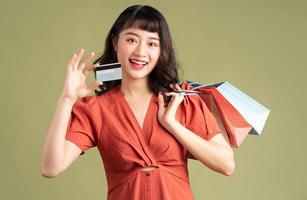 aziatische vrouw die een boodschappentas vasthoudt en een bankkaart omhoog houdt