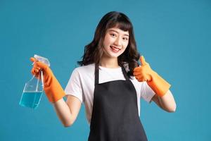 een foto van een Aziatische vrouw in een schort en handschoenen die zich voorbereiden op de schoonmaakklus