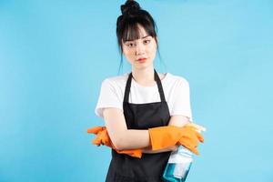 Aziatische huisvrouw draagt oranje handschoenen en houdt een straal water in haar hand