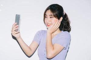 jonge aziatische vrouw die smartphone op witte achtergrond gebruikt