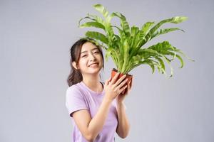 jonge aziatische vrouw die potten op grijze achtergrond houdt foto