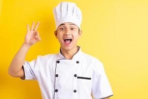 afbeelding van Aziatische mannelijke chef-kok op gele achtergrond foto