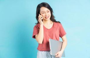 mooie aziatische vrouw die laptop in de hand houdt tijdens het bellen