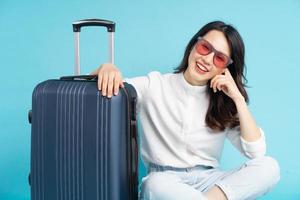 mooie aziatische vrouw die naast de koffer zit en zich voorbereidt op reizen foto