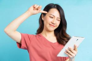 mooie aziatische vrouw die tablet in de hand houdt en positief denkt