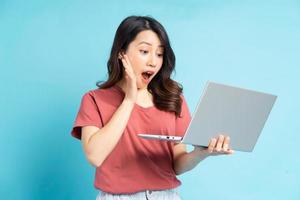 mooie aziatische vrouw die laptop gebruikt met een verbaasd gezicht foto