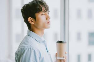 Aziatische zakenman drinkt koffie bij het raam foto