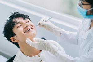 Aziatische vrouwelijke arts die de tanden van een patiënt controleert foto