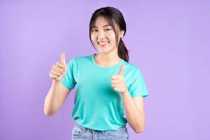 jong Aziatisch meisje in cyaan shirt op paarse achtergrond foto
