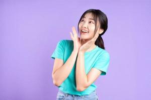jong Aziatisch meisje in cyaan shirt op paarse achtergrond foto