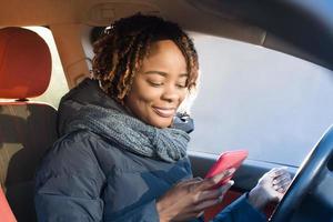 gelukkige Afro-Amerikaanse vrouw in een auto rijden, herfst-winter foto