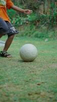 een jongen Toneelstukken een plastic voetbal bal Aan de gras. foto
