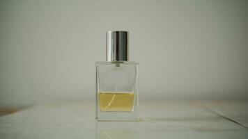klein transparant parfum fles gevulde met geel vloeistof Aan tafel met minimalistische wazig achtergrond. foto