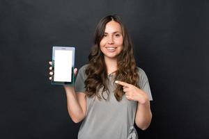 foto van lachende jonge vrouw wijzend op een leeg scherm op tablet