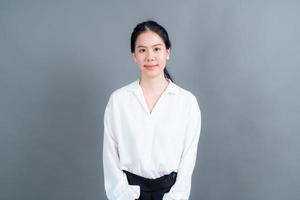 gelukkige aziatische vrouw met blij gezicht in wit overhemd op grijze achtergrond foto