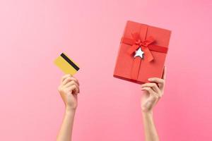 handen met rode geschenkdoos en bankkaart op roze achtergrond foto
