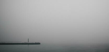 de pier de waterkant eng en eenzaam achtergrond waterkant smog donker toon beeld foto