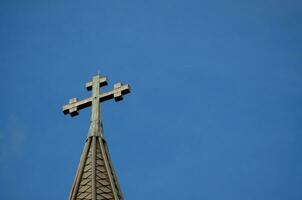 kruis staand Aan een kerk dak , geometrisch figuur bestaande van twee kruisende lijnen of bars tegen de blauw lucht. foto