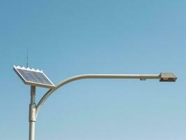 zonne- cel straat lamp met lang arm staand tegen blauw lucht dag, gebruik de macht van de zon naar voorzien gemakkelijk verlichting oplossingen voor buitenshuis gebieden. foto