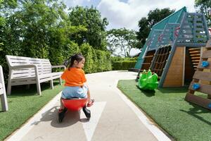 schattig Aziatisch kind meisje glimlach Speel speelgoed- auto Aan school- of kleuterschool werf of speelplaats. gezond zomer werkzaamheid voor kinderen. kind spelen Aan buitenshuis speelplaats. baby kind werkzaamheid concept. foto