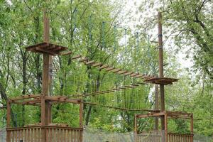 extreem avontuur beklimming hoog draad park. behendigheid Aan touw kabels pad. buitenshuis amusement centrum voor kinderen. Woud familie weekend vrije tijd werkzaamheid. balans straal en touw suspensie bruggen foto