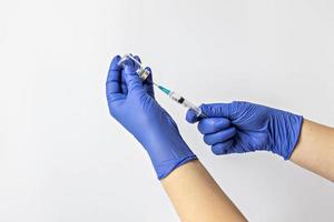 een medisch werker in medische handschoenen trekt een dosis coronavirusvaccin in een spuit. het concept van vaccinatie, immunisatie, preventie van mensen van covid-19 foto