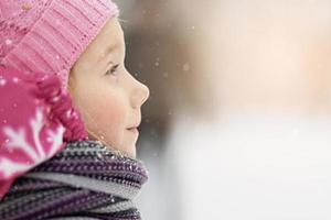 portret van een klein meisje in roze close-up. een kind geniet van de sneeuwval. Kerstvakantie