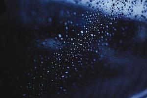 druppels water op het glas. regen buiten het raam. blauwe textuur achtergrond. bewolkte regenachtige dag foto