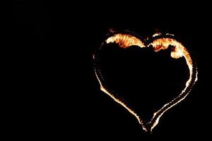 brandend hart met vlammen. geïsoleerd op een donkere achtergrond. vuurshow in de nacht. gelukkige valentijnskaart. Bengaals vuur brandend hart. ruimte voor tekst. bruiloft of Valentijn concept. gelukkig nieuwjaar. foto