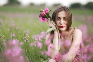 mooi portret van een meisje met roze bloemen. meisje op het gebied van bloemen. bordeauxrode pioen, landschap foto