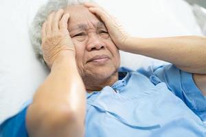 Aziatische senior of oudere oude dame vrouw patiënt hoofdpijn zittend op bed in verpleegafdeling ziekenhuis, gezond sterk medisch concept foto