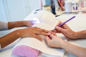 close-up van schoonheidsspecialiste die de nagels van een vrouw schildert met een borstel in een nagelsalon foto