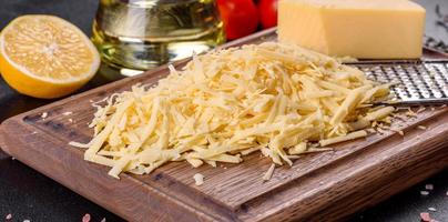 verse harde kaas geraspt op een grote rasp op een houten snijplank foto