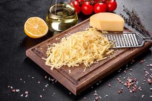verse harde kaas geraspt op een grote rasp op een houten snijplank foto