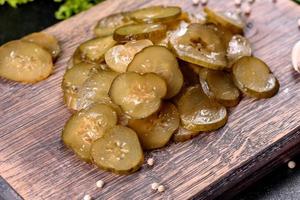smakelijke zoute pittige ingelegde komkommer gesneden met ringen op een houten snijplank foto