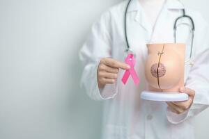 roze oktober borst kanker bewustzijn maand, dokter vrouw met roze lint en borst anatomie model. nationaal kanker overlevenden maand, Gezondheid diagnose, moeder en wereld kanker dag concept foto
