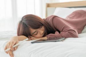 mooie aziatische vrouw die met tablet op bed werkt
