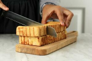 vrouw hand- besnoeiing roti bakar of Bandung geroosterd brood brood foto