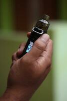 Mens hand- Holding vapen pen metaal elektronisch sigaret met vervagen achtergrond foto