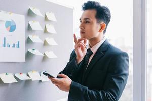Aziatische zakenman die een bedrijf plant naast het planbord foto