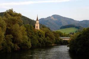 uitzicht op de rivier de mur met kerk in leoben, oostenrijk foto