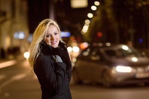 mooie, blonde vrouw in autolichten in de nachtstad. foto
