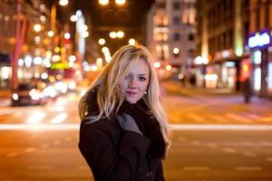 mooie, blonde vrouw in autolichten in de nachtstad. foto