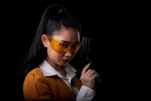 asea-vrouw die een geel pak draagt, een hand met een pistool op een zwarte achtergrond foto